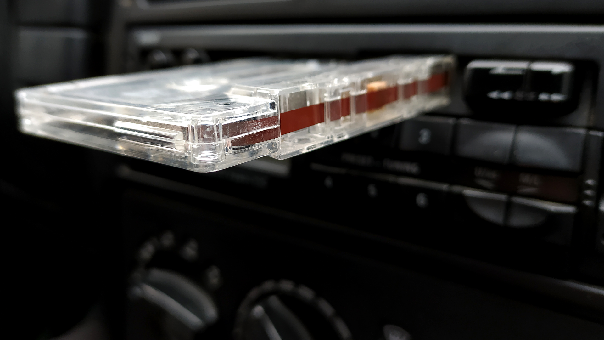 A tape deck inside a car with a cassette hanging out.