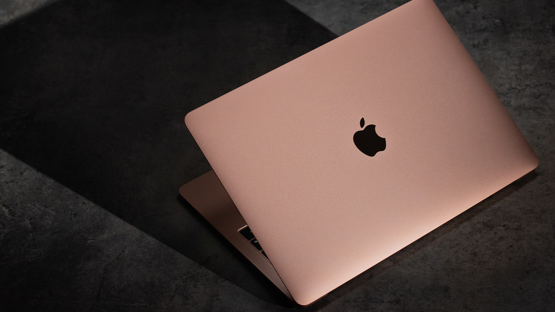 A rose gold MacBook Air on a table.