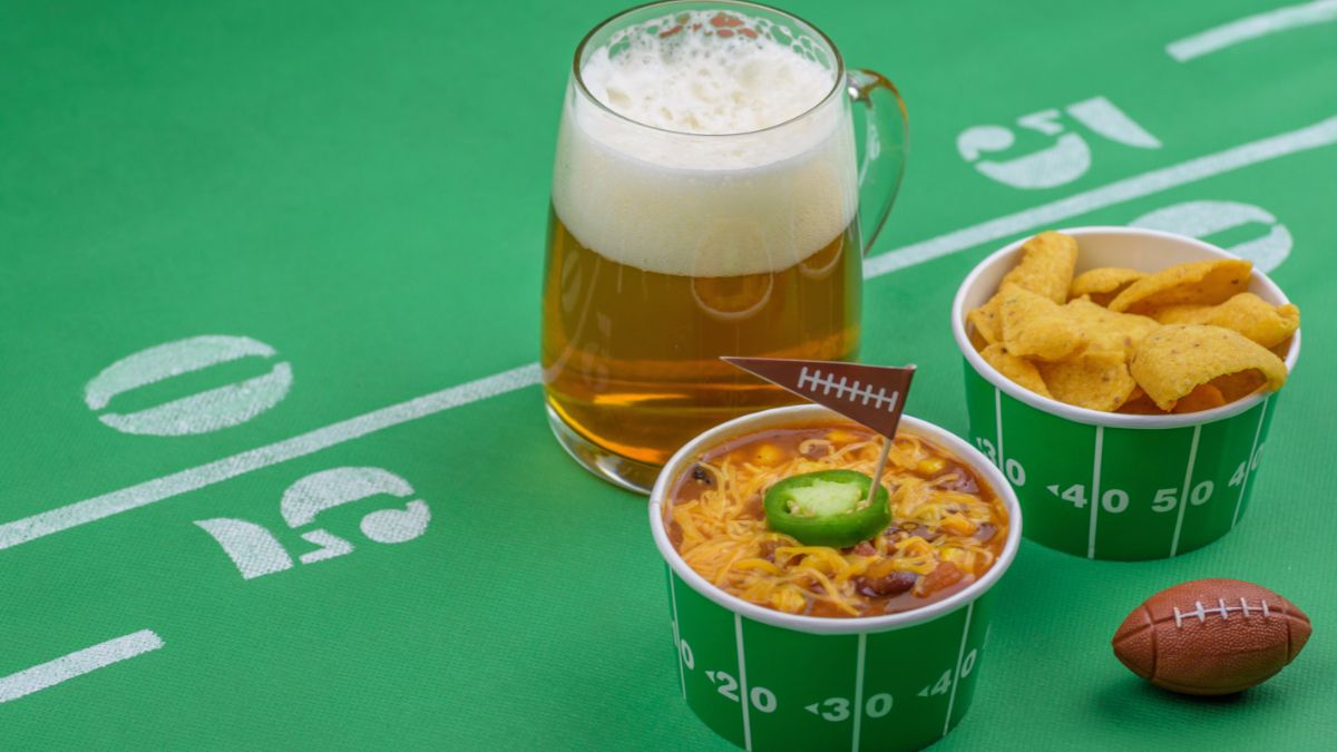 Football-themed table with football-themed chili bowls and a glass of beer