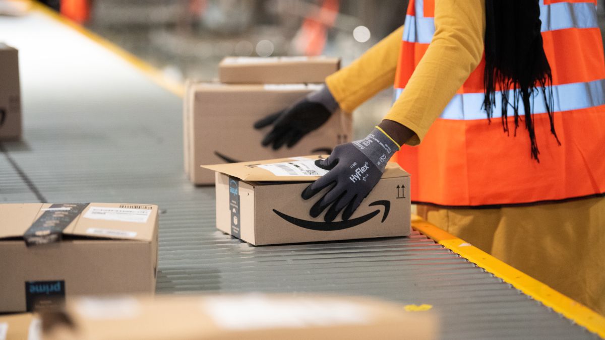 An Amazon employee handling a package on a conveyor belt.