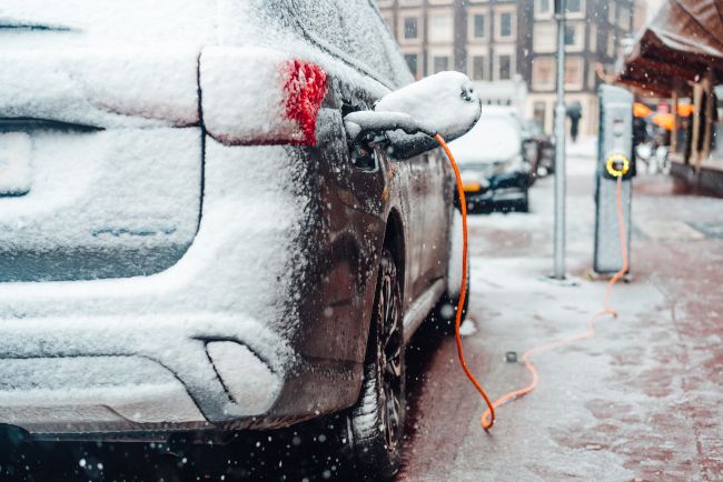 An electric car parked and charging in the snow.