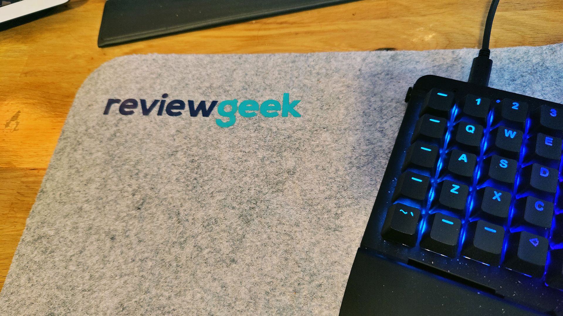 A felt desk mouse mat with the words Review Geek on it