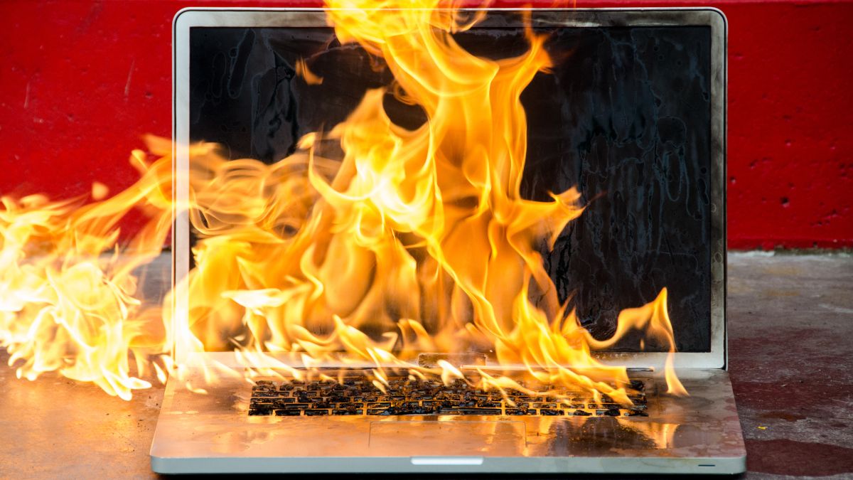 A laptop on fire, engulfed in flames.