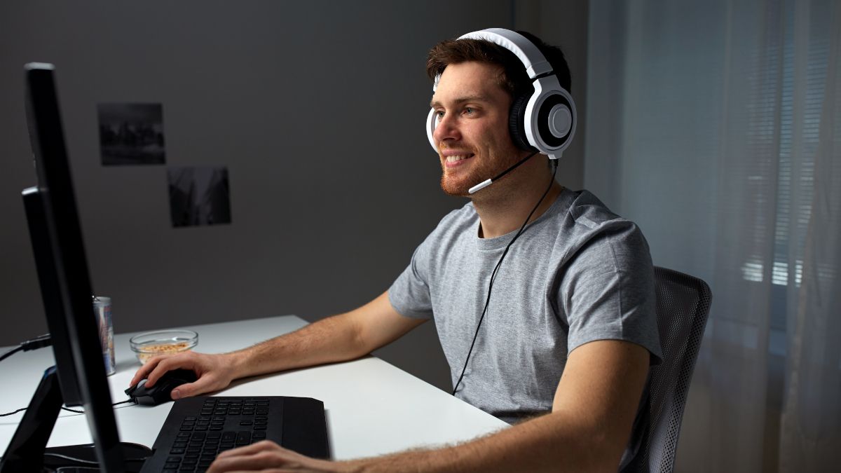 Male gamer smiling and using a desktop PC.