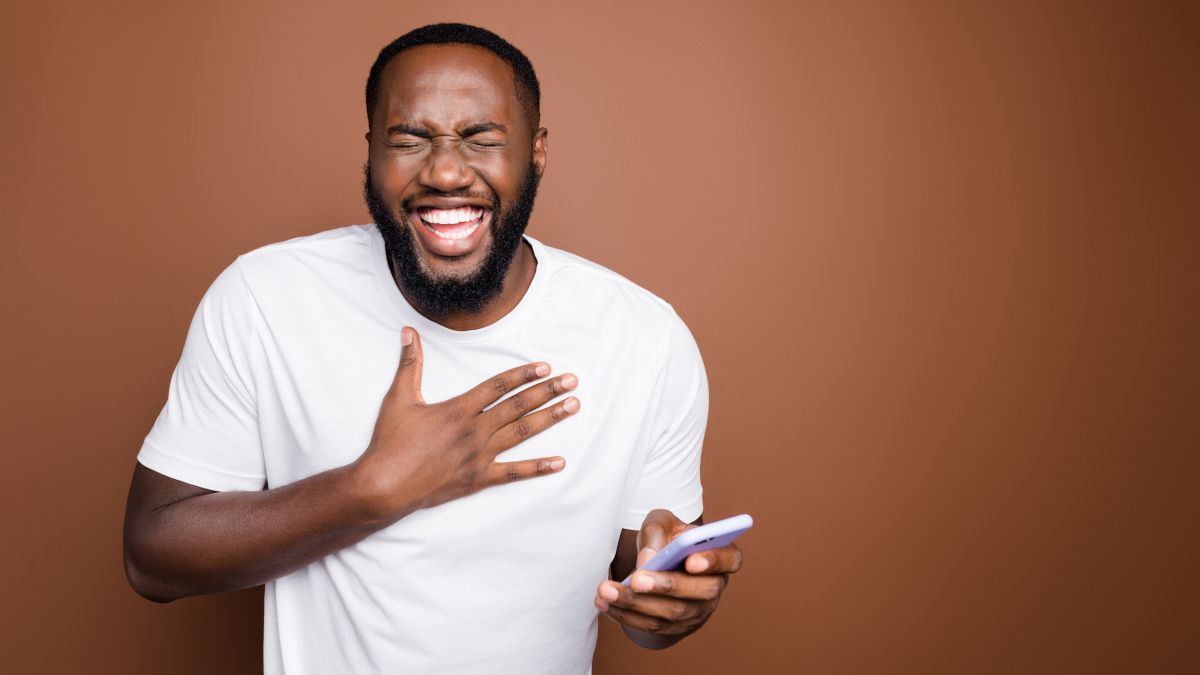 Man laughing while holding a smartphone.