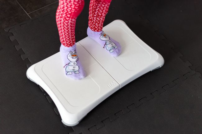 A child standing on a Wii balance board.