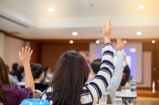 Business people raising hands to ask questions in a conference.