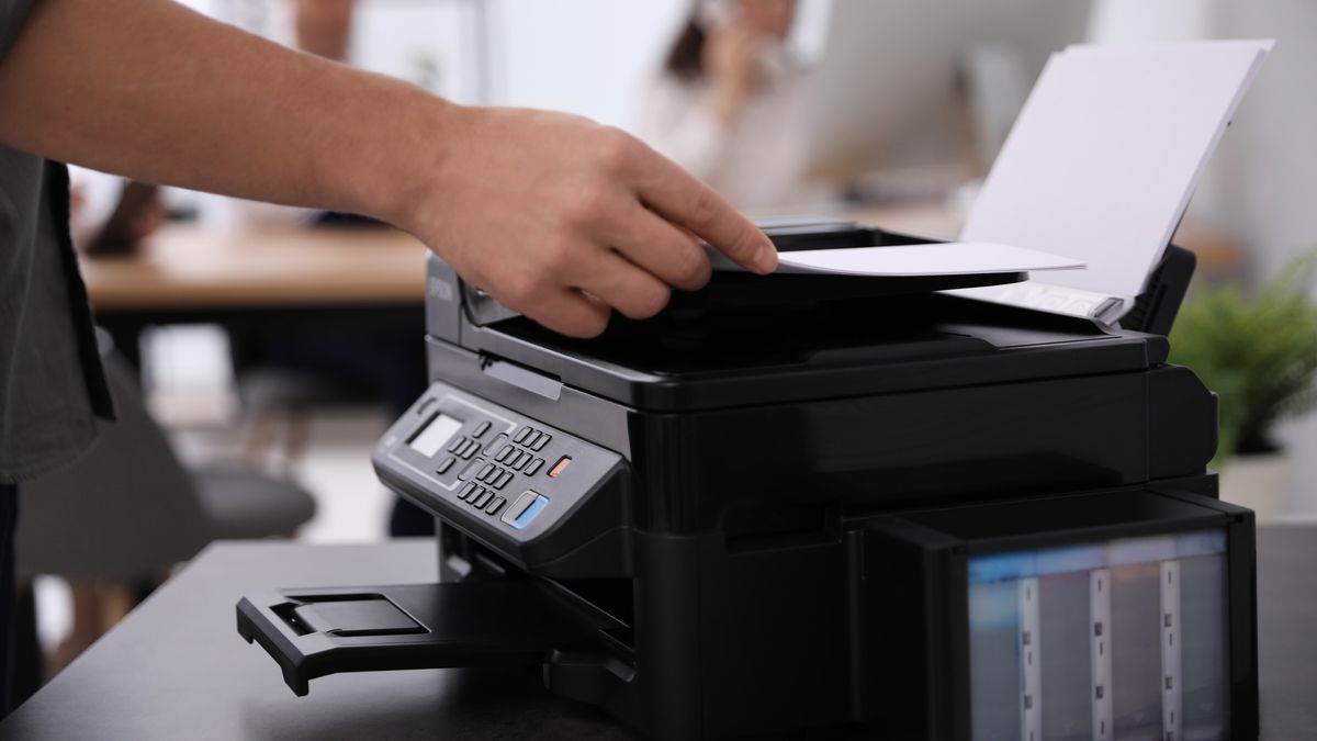 A person using an all-in-one printer in an office setting.