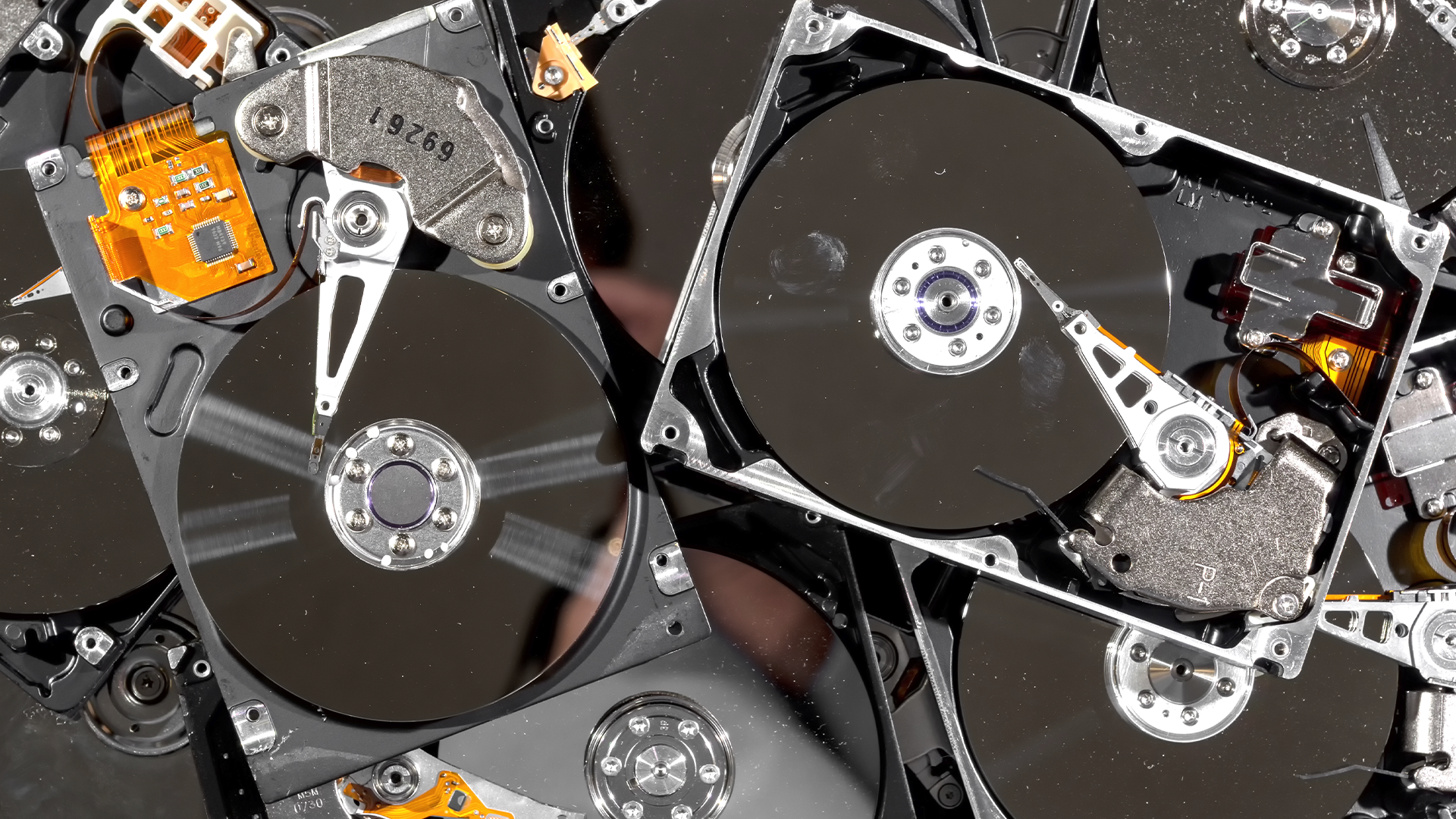 A pile of hard drives with their discs exposed. There's nasty dust and fingerprints all over the drives.