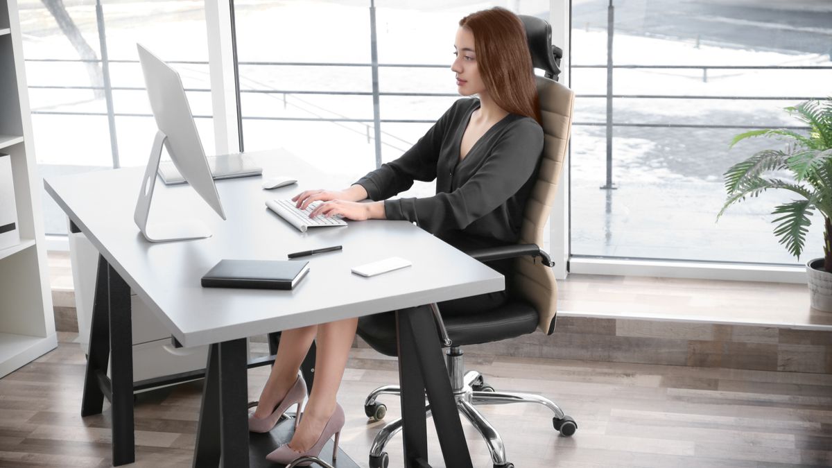 Woman working in an office with ergonomic seating.