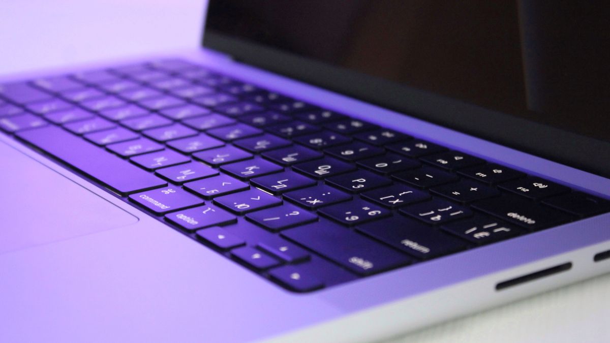 Closeup of a MacBook Pro M1 under purple lighting.