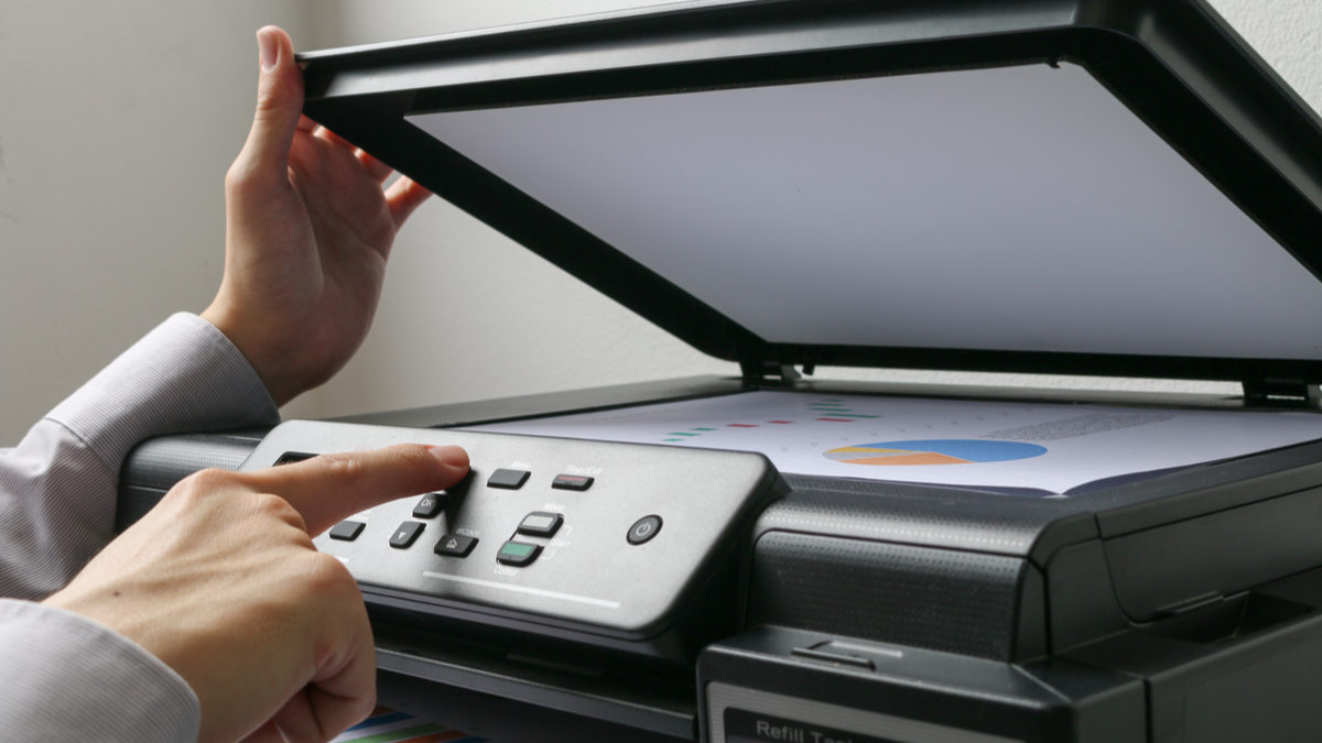 Person pressing a button on a large scanner.