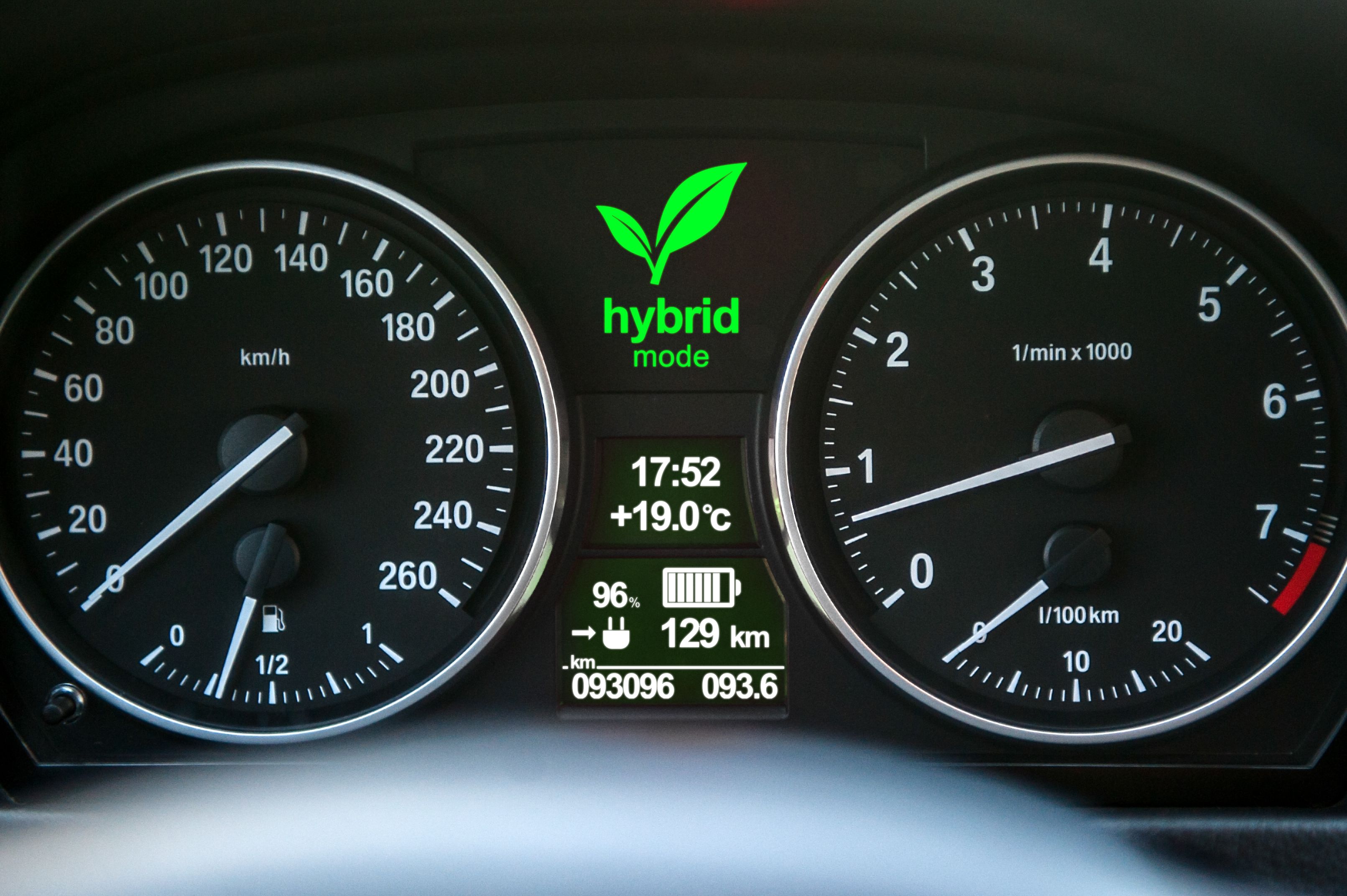 Closeup of a hybrid car's dashboard display with the "Hybrid Mode" light activated.