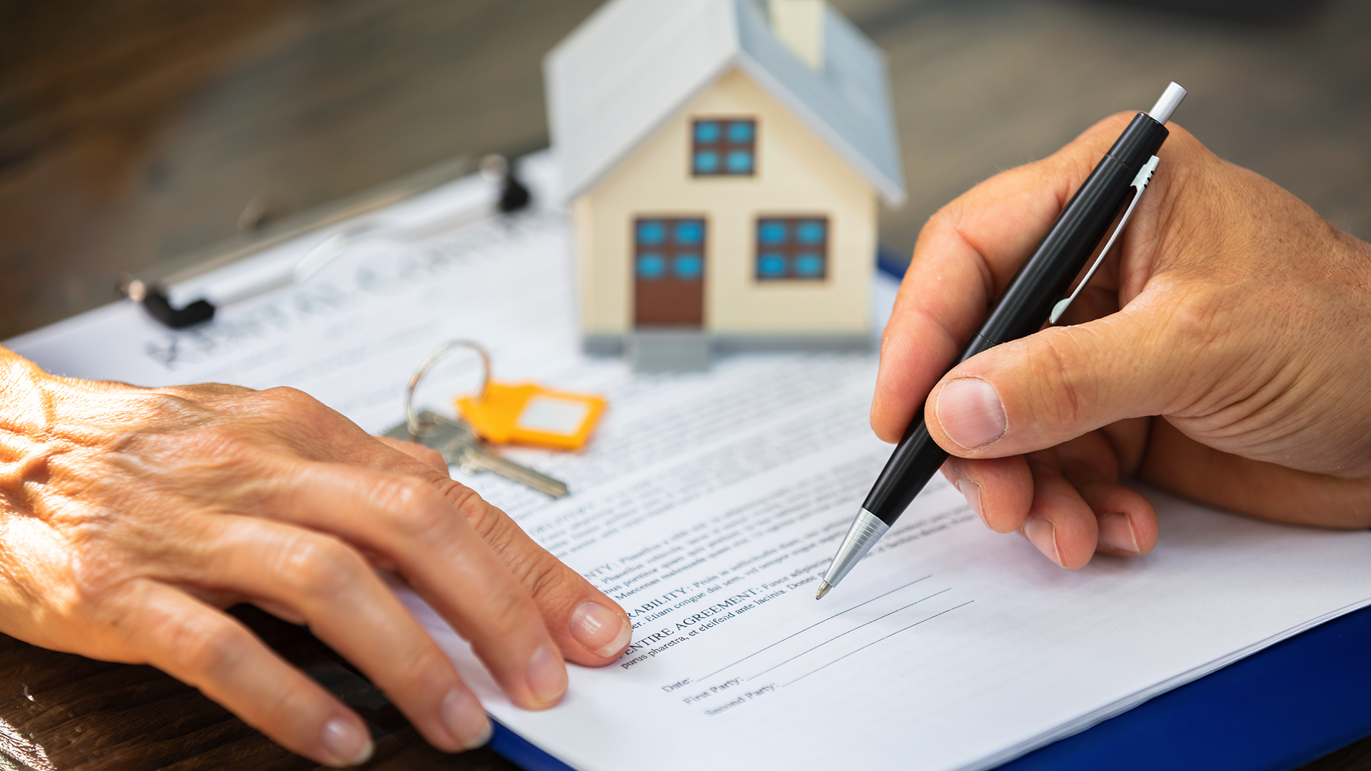 A person signing a deed or contract for a home.