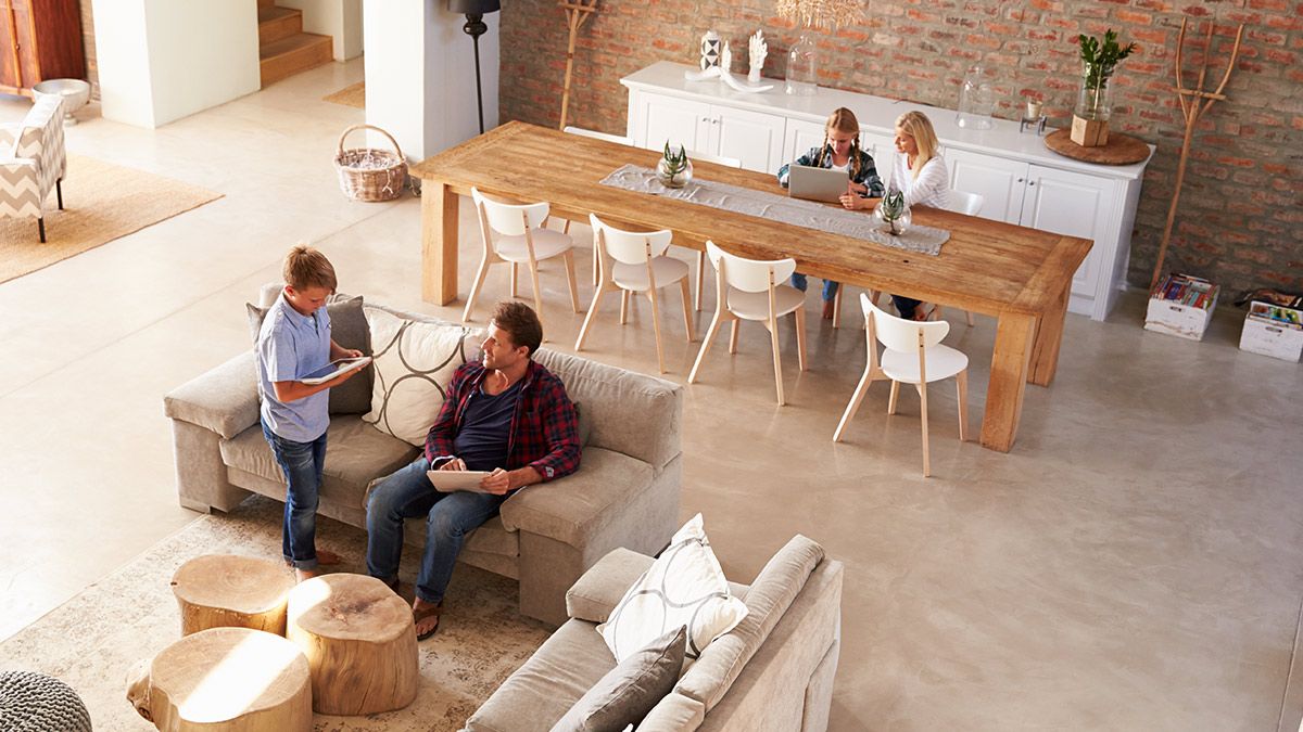 A family using tablets and laptops in an airy open-concept living space.