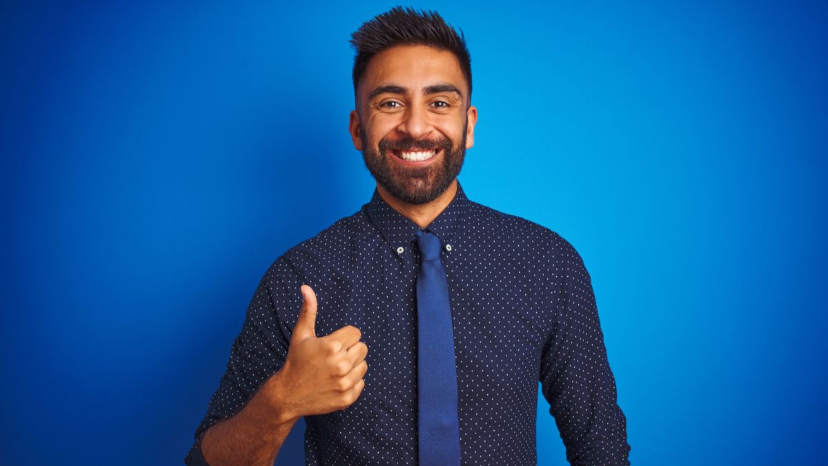 Businessman grinning and giving a thumbs-up gesture.
