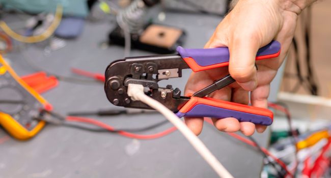 Person using a crimper on an Ethernet cable.