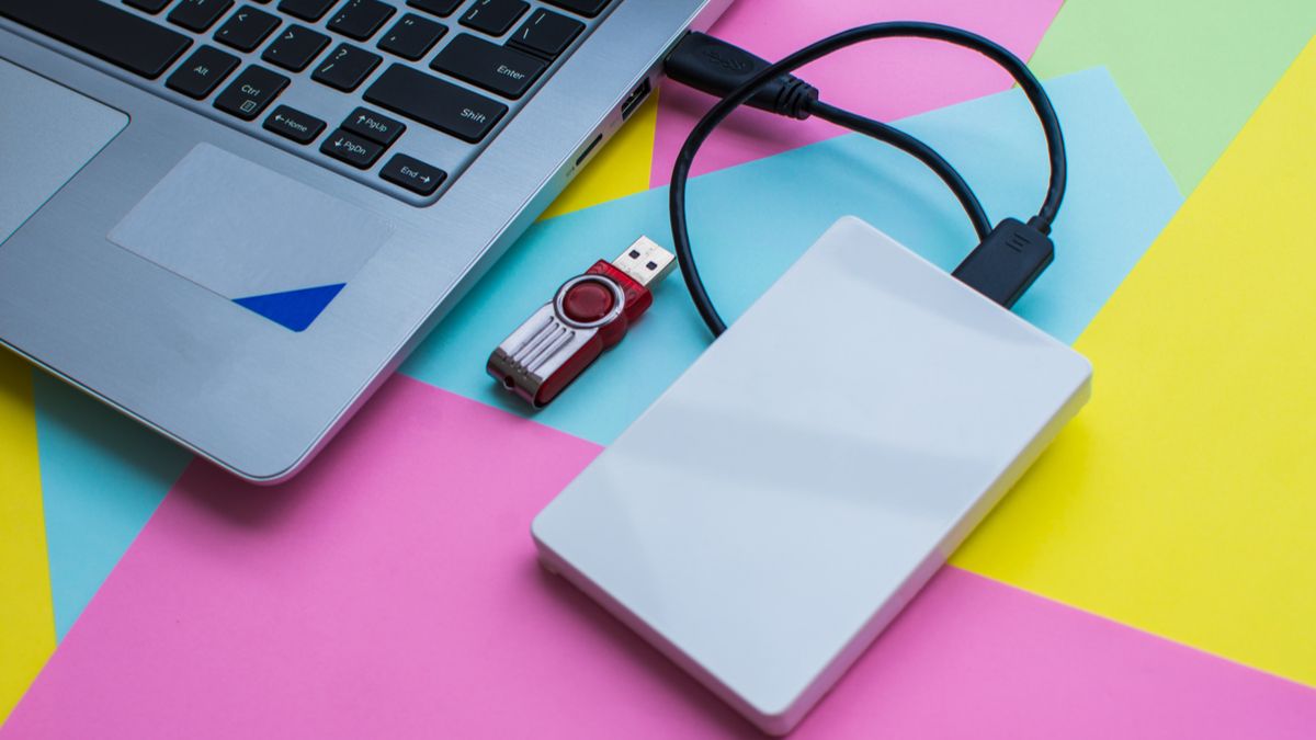 An external hard drive connected to a laptop next to a USB drive.