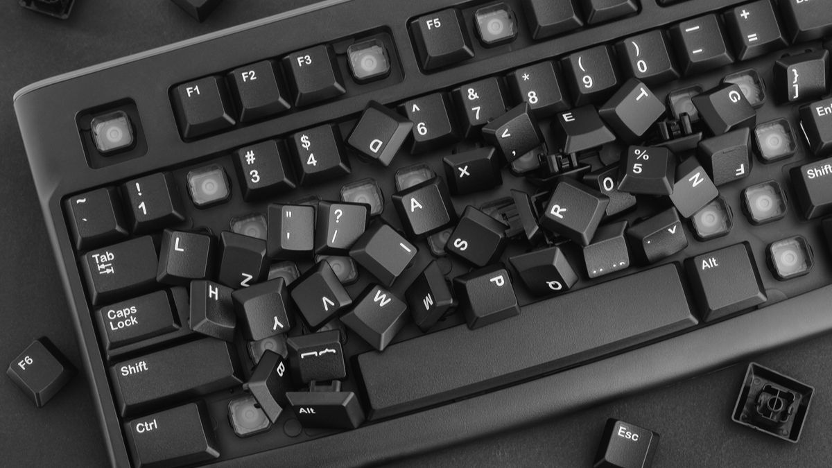 A keyboard with its keys removed and scattered.