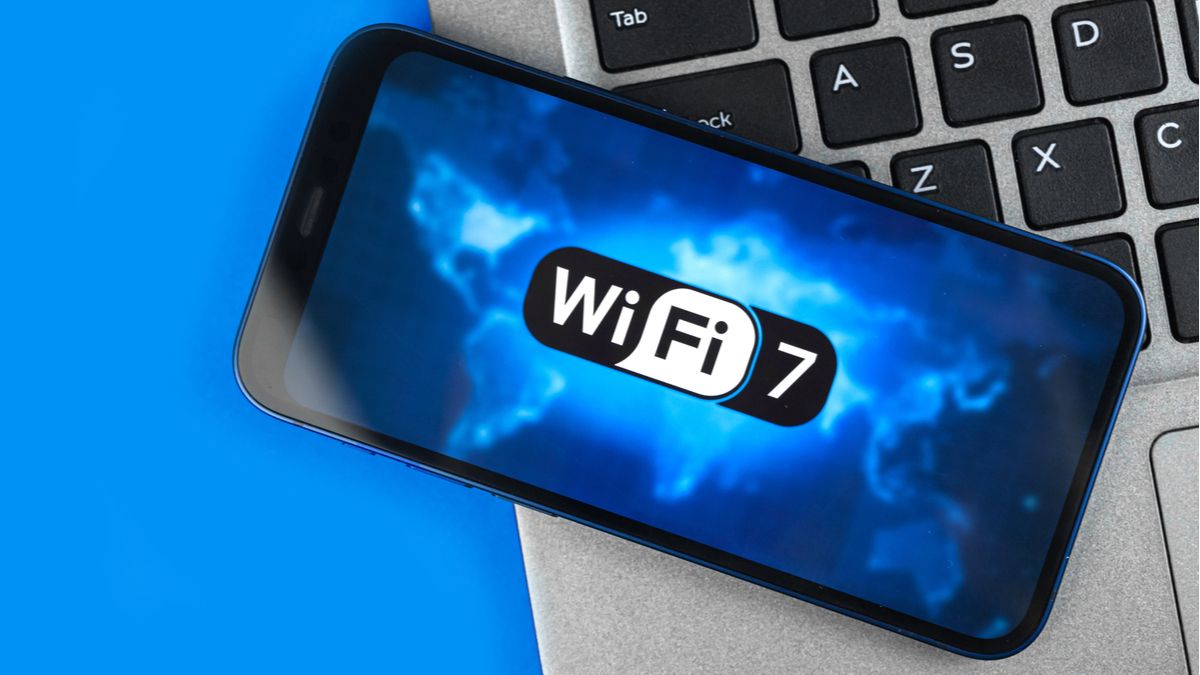 Smartphone on top of a laptop, showing the Wi-Fi 7 logo on display.
