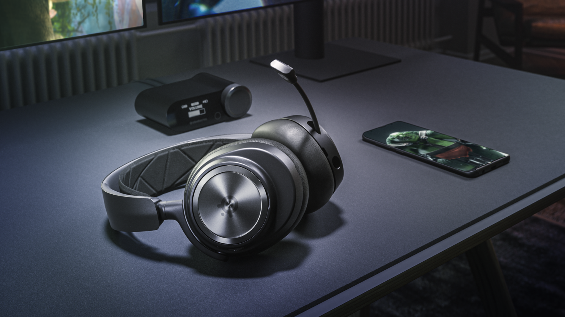 The SteelSeries Arctis Nova Pro wireless headphones on a desk next to its base station