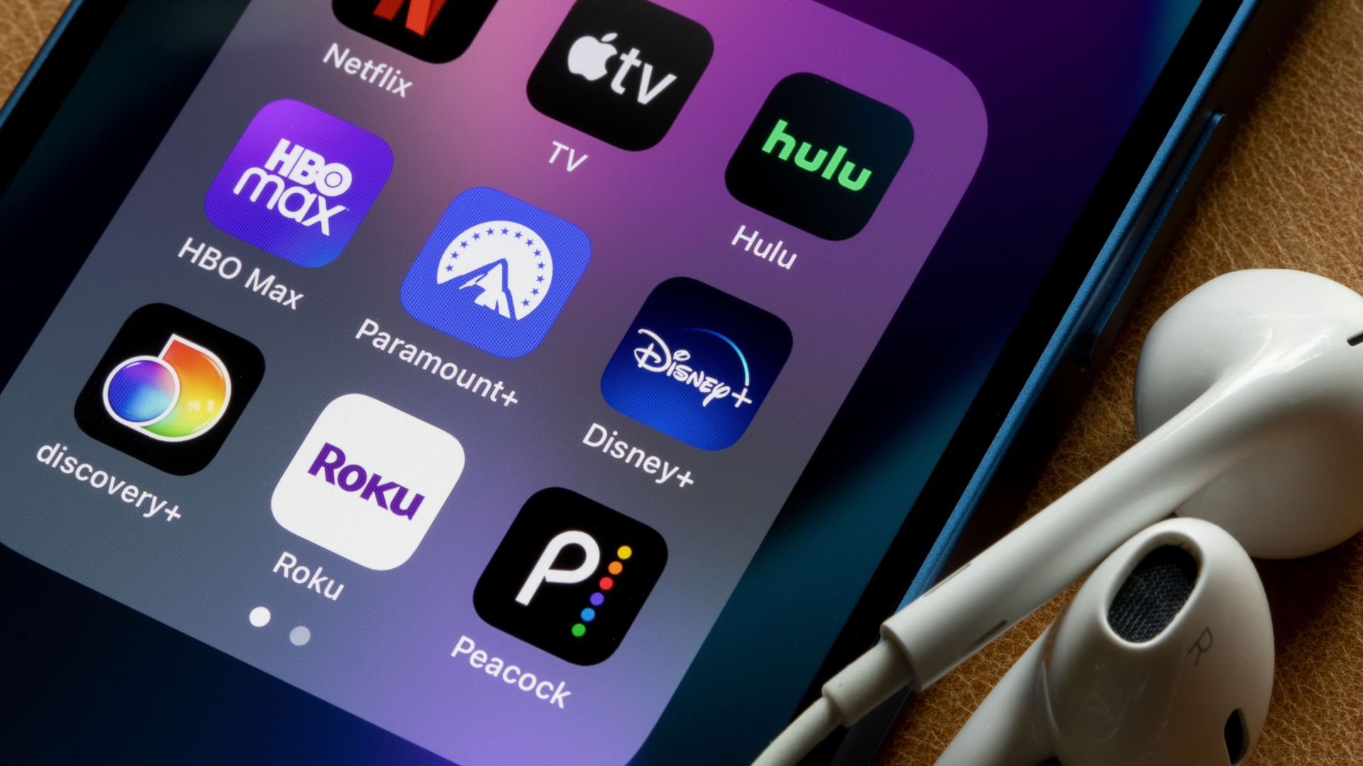 Assorted streaming apps are seen on an iPhone, including Netflix, Apple TV, Hulu, HBO Max, Paramount Plus, Disney Plus, Discovery Plus, Roku, and Peacock.