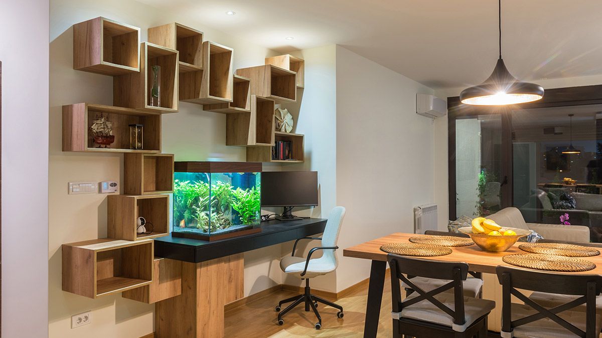 A dining room with a wall-mounted desk holding a fish tank.