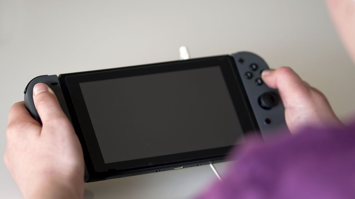 Person pressing buttons on a Nintendo Switch with the screen turned off.