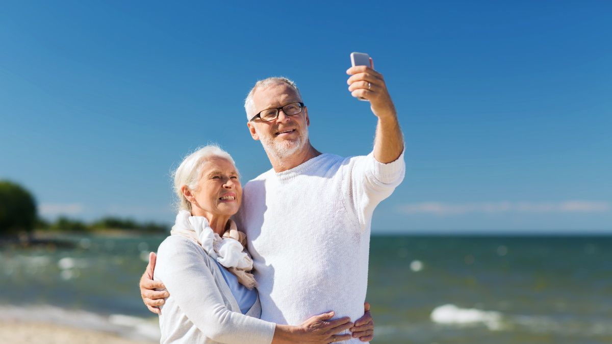Seniors on a beach holding a cell phone.