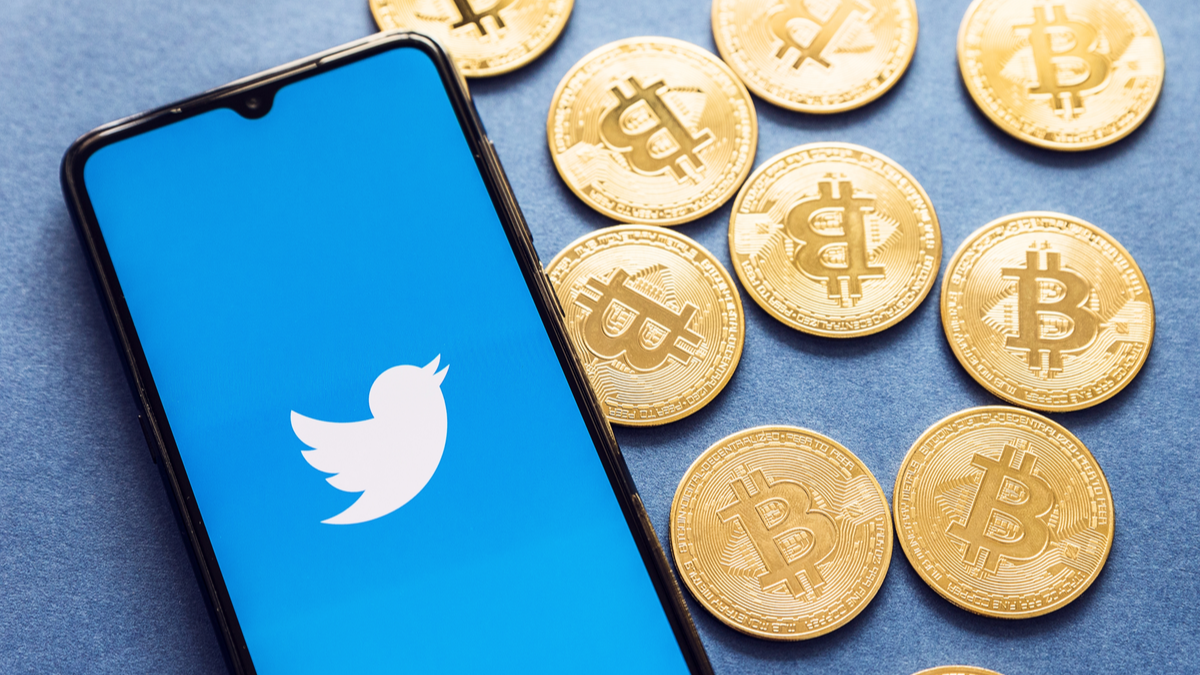 The Twitter app on a smartphone with Bitcoin coins next to it.