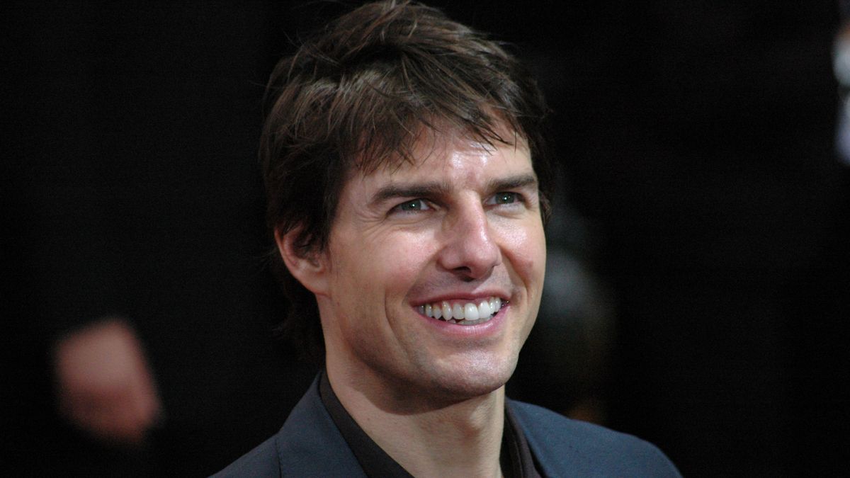 Actor Tom Cruise smiling for cameras at a film premiere.