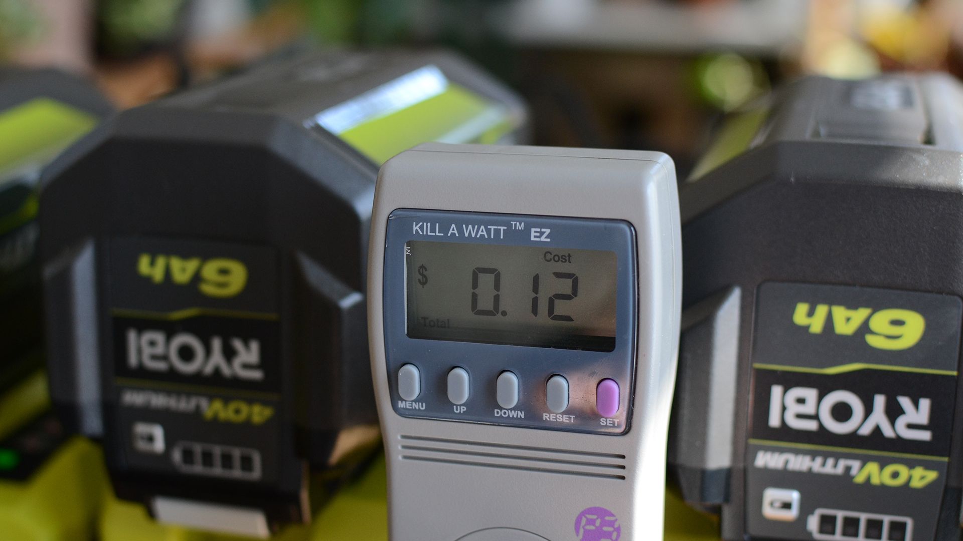 A closeup view of a Kill A Watt meter charging some Ryobi batteries.