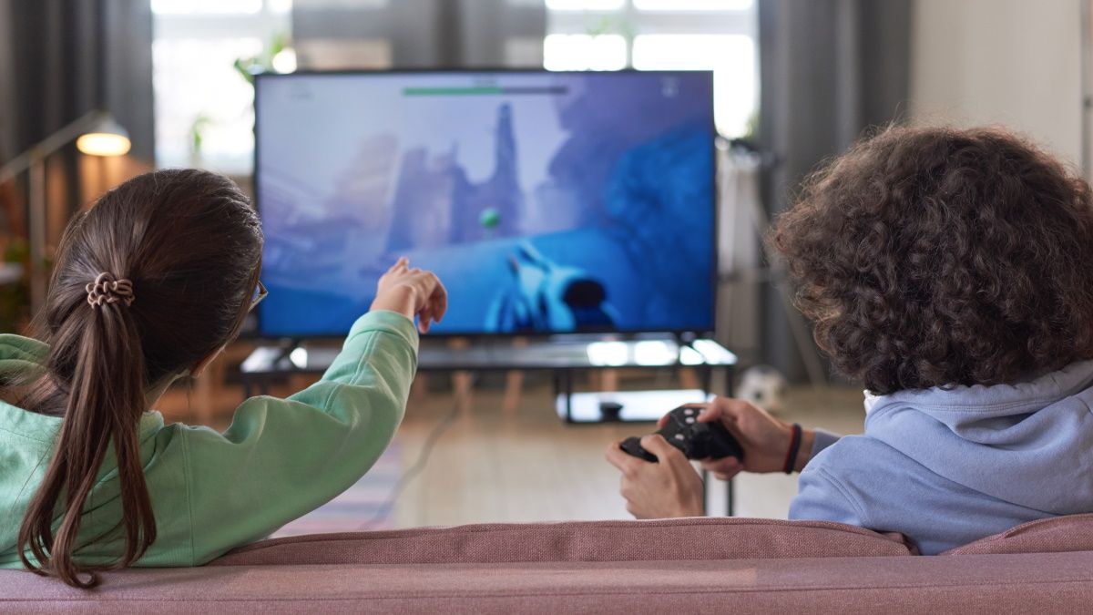 People sitting on a couch while playing a video game on a TV.