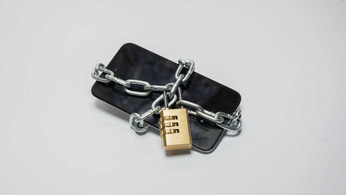 Smartphone wrapped in a metal chain with a padlock securing it.