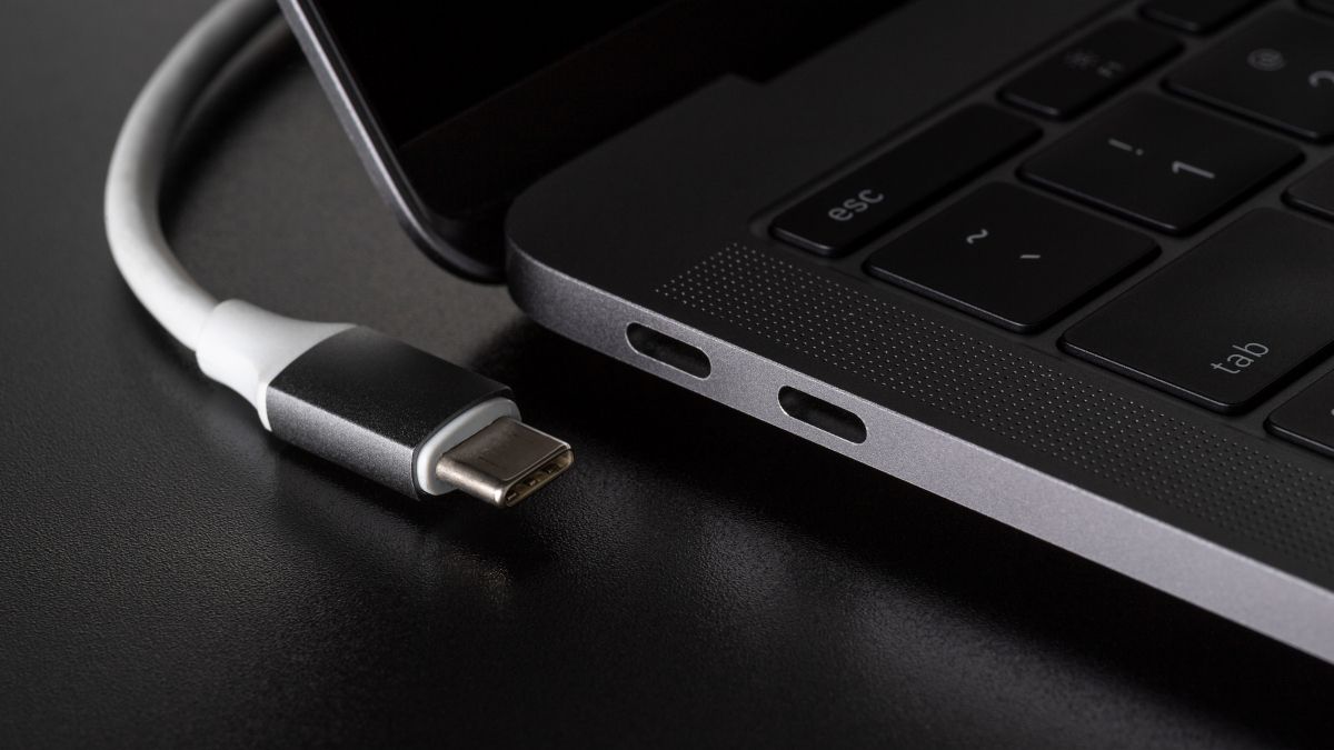 A USB Type-C cable disconnected from a port on a laptop.