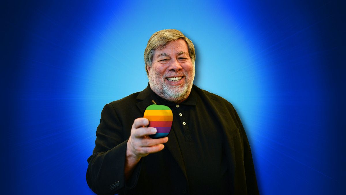 Steve Wozniak holding a six-colored apple on a blue background in 2014