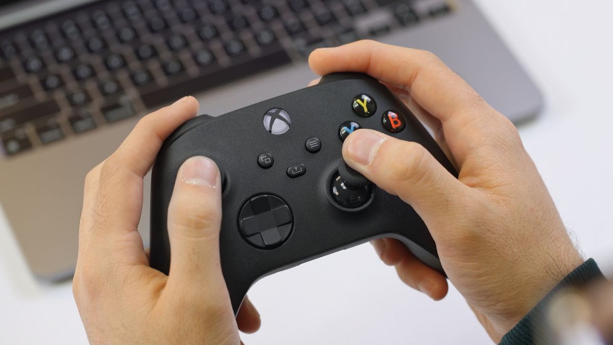 Hands holding an Xbox Series X wireless controller over a MacBook Pro M1.