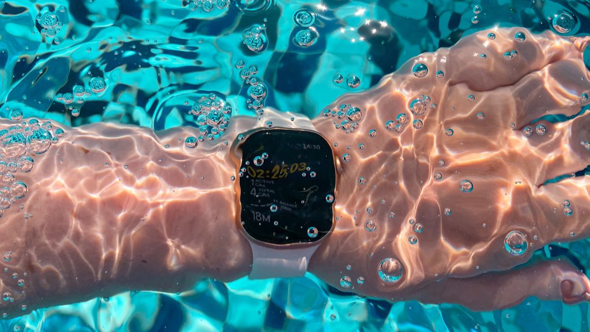 An Apple Watch on a person's wrist submerged underwater.