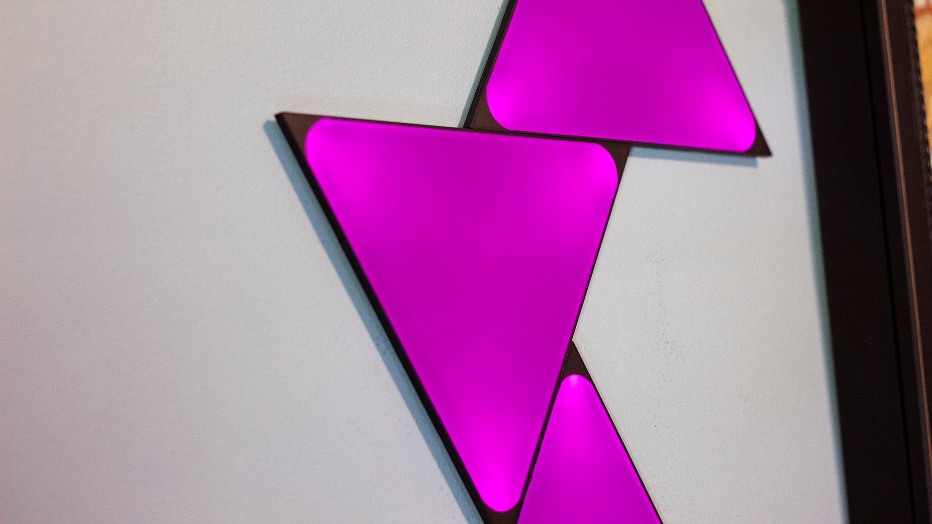 A set of triangles on a wall glowing purple