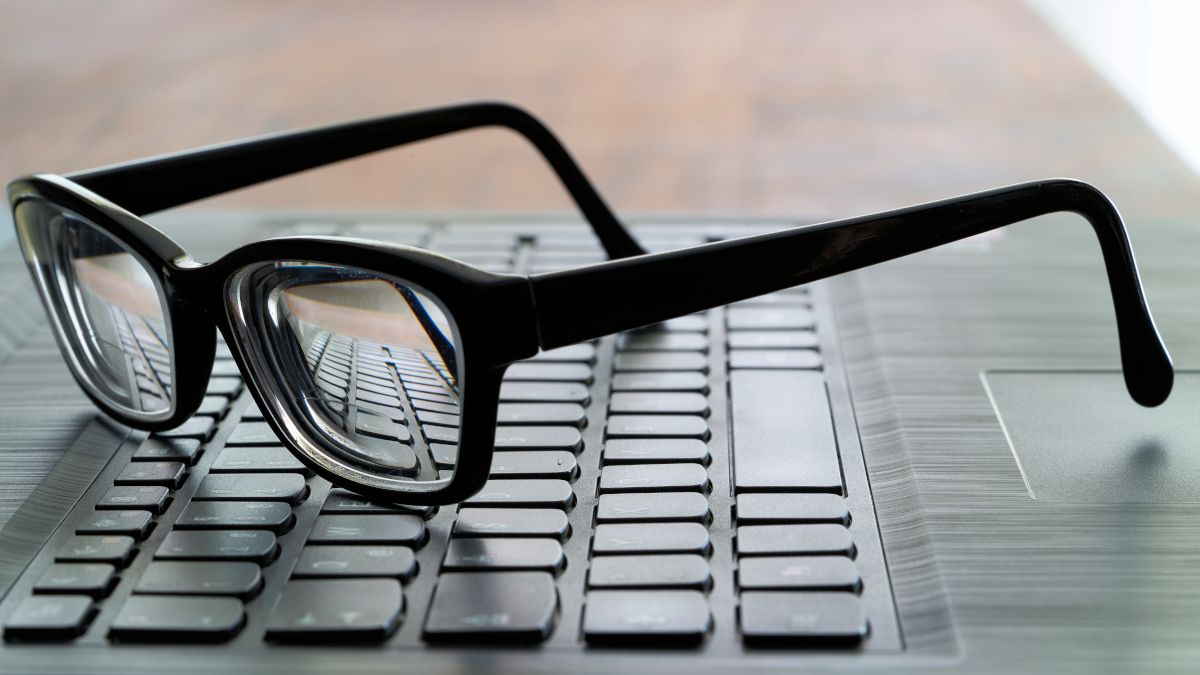 A pair of glasses set on top of a laptop keyboard.