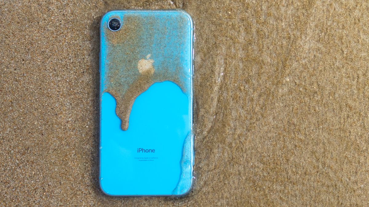 A blue iPhone XR covered in sand and water.