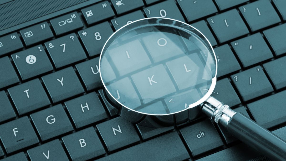 A magnifying glass on top of a laptop keyboard.