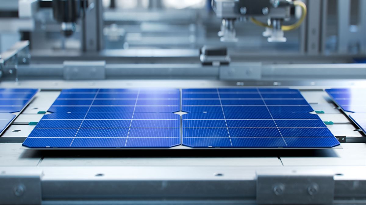 Solar panels being moved in a manufacturing facility.