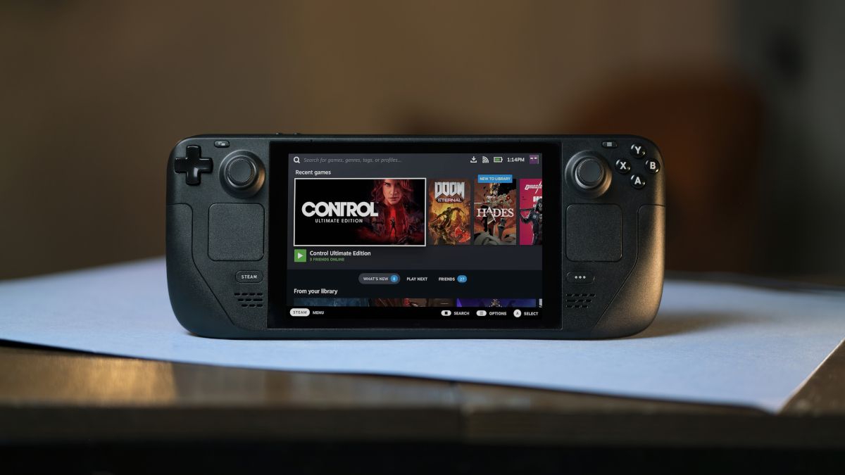 A Steam Deck gaming console showing a selection of games onscreen and sitting on a tabletop.