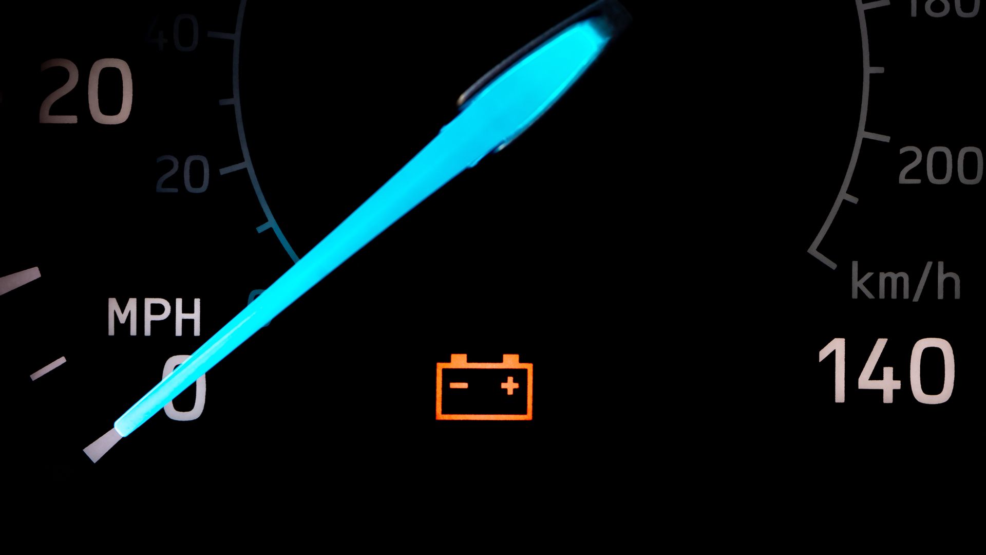 Closeup of a car battery warning light on dashboard.