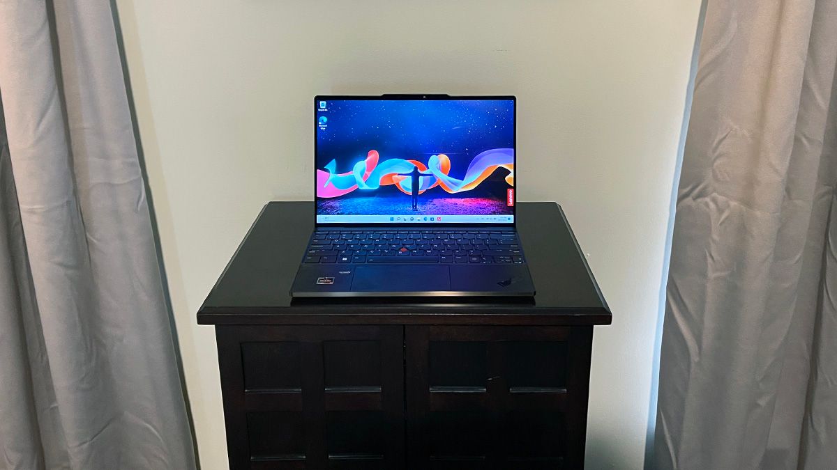 An open Lenovo ThinkPad Z13 Gen 1 Touchscreen Notebook on a table top between two curtains