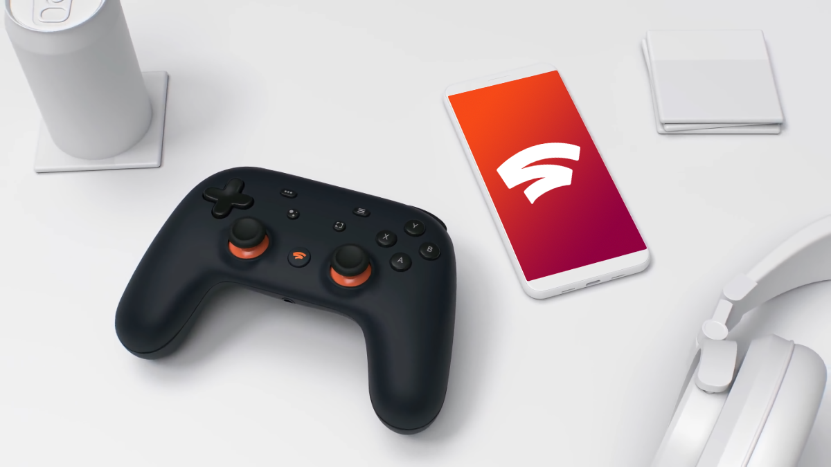 Google Stadia Founders controller sitting on a table beside a phone with a Google Stadia logo on it
