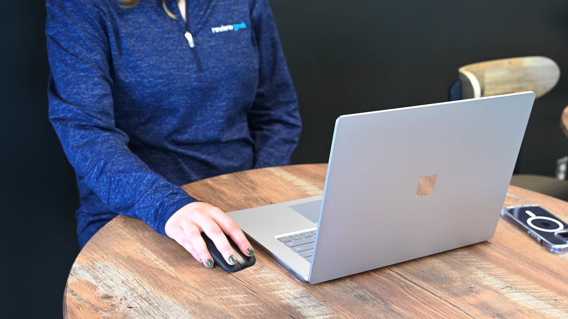 A person using a MIcrosoft Surface Laptop with a portable mouse.