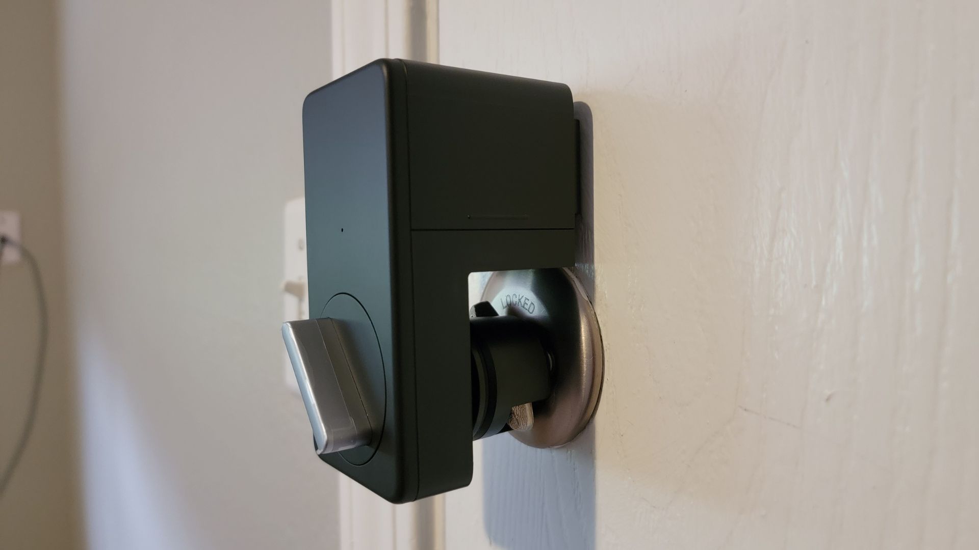 closeup of the switchbot lock installed over a white apartment door