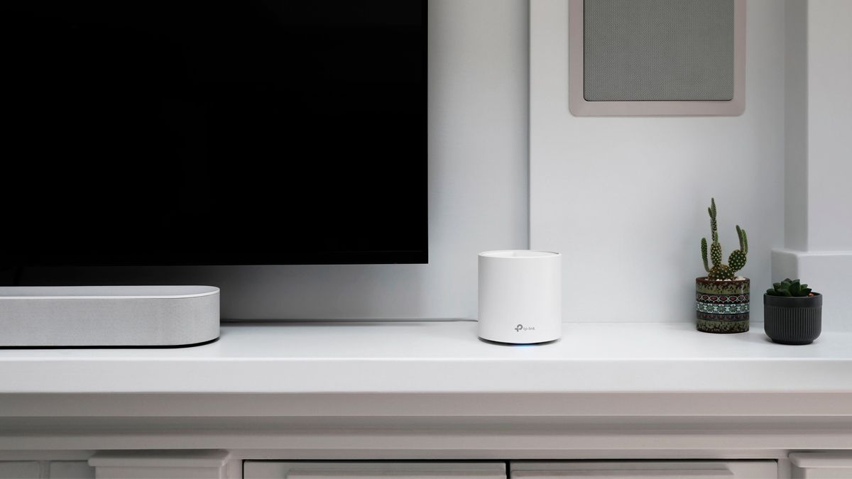 A TP-Link Deco Wi-Fi mesh node sittign next to a TV.
